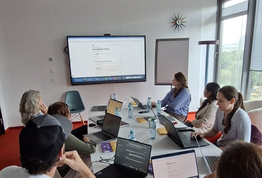 Gruppe schaut gemeinsam auf einen Bildschirm mit einer Arbeitsliste